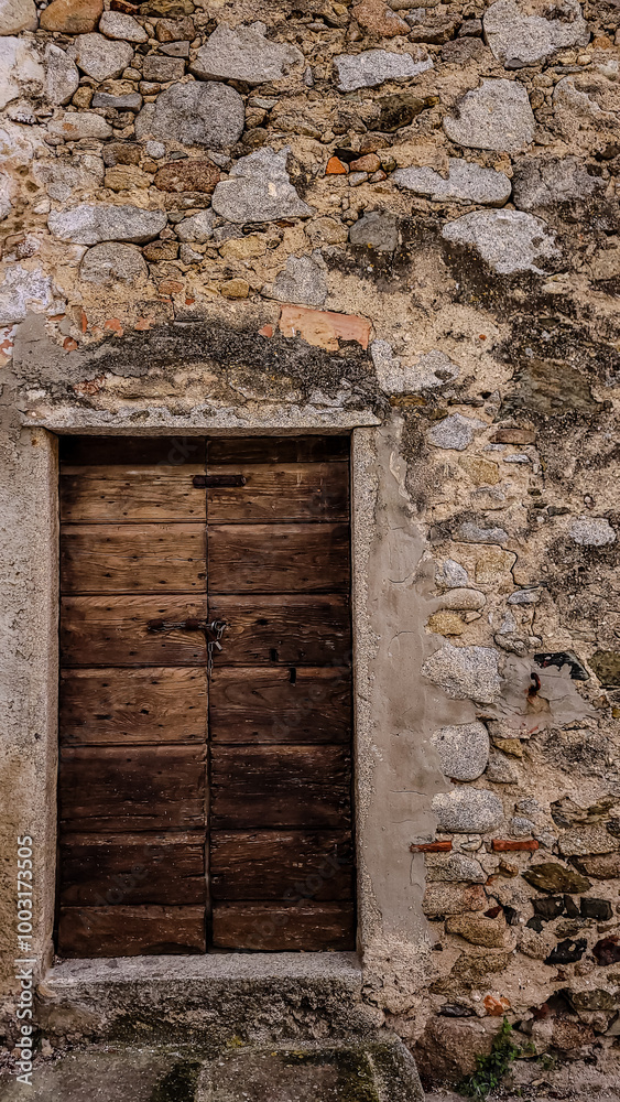 Entrance to an old stone house. Dark brown wood, stone stairs, rusted iron and natural stone. Entrance to an old stone house. Dark brown wood, stone stairs, rusted iron and natural stone.