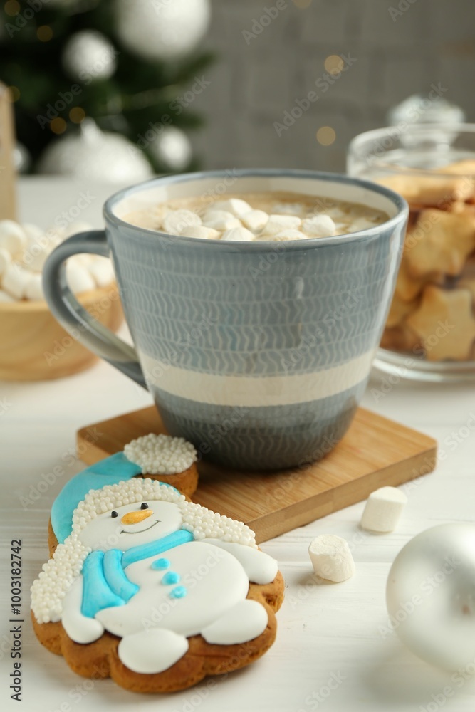 Delicious cookie in shape of snowman, cup with cocoa and Christmas decor on white wooden table, closeup Delicious cookie in shape of snowman, cup with cocoa and Christmas decor on white wooden table, closeup
