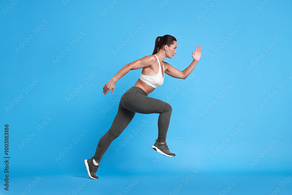 Obraz premium Woman in sportswear running on light blue background
