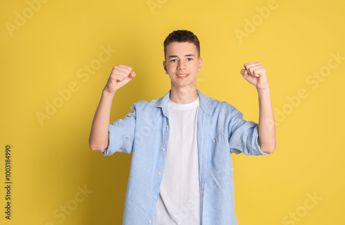 Portrait of happy teenage boy on yellow background