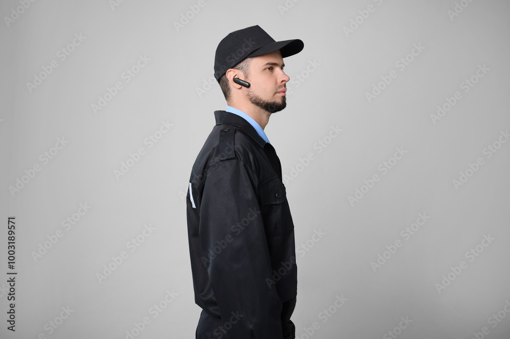 Security guard in uniform with earpiece on grey background Security guard in uniform with earpiece on grey background