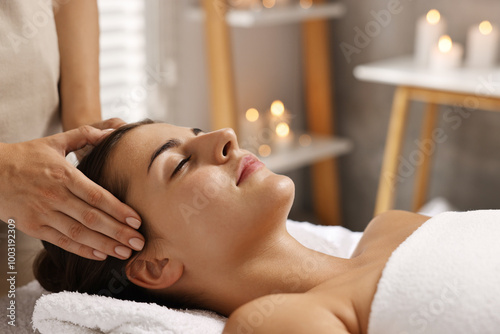 Attractive woman enjoying face massage in spa salon, closeup