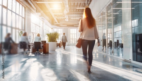 Blurred background of an open-plan office interior with young women walking and people working. business people walking in corridor office building. Motion blur