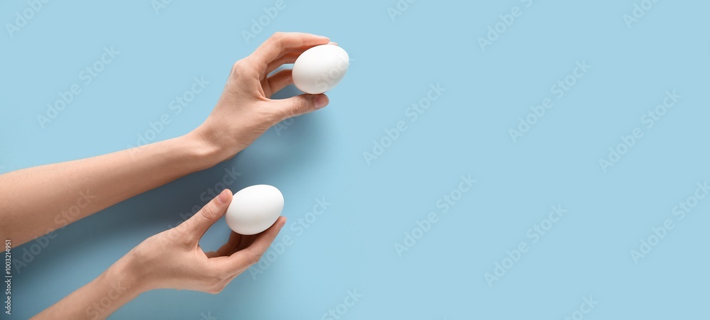 Hands holding raw chicken eggs on light blue background with space for text Hands holding raw chicken eggs on light blue background with space for text