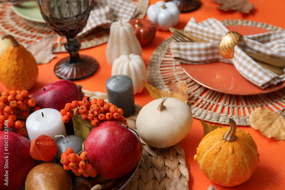 Stylish table setting with candles and autumn decor on orange background Stylish table setting with candles and autumn decor on orange background