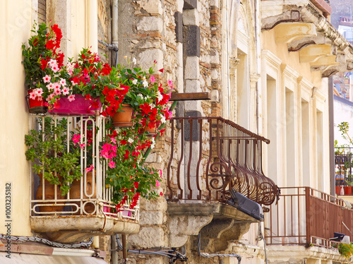 Fototapeta Naklejka Na Ścianę i Meble -  Building facades and balconies in Taormina streets full of bougainvillea flowers in a sunny summer day, Sicily, Italy 