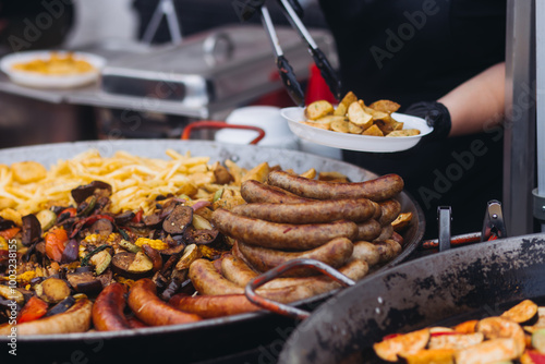 Food festival with food stall kiosk, open-air outdoor fair market, assortment of different traditional European grilled barbecued street food with sausages, bbq, chicken, pork and lamb on a large pan
