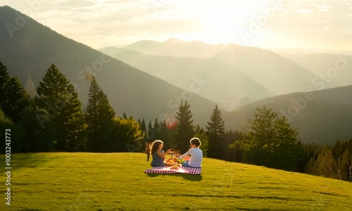 A family enjoying a picnic in a lush green park surrounded by mountains