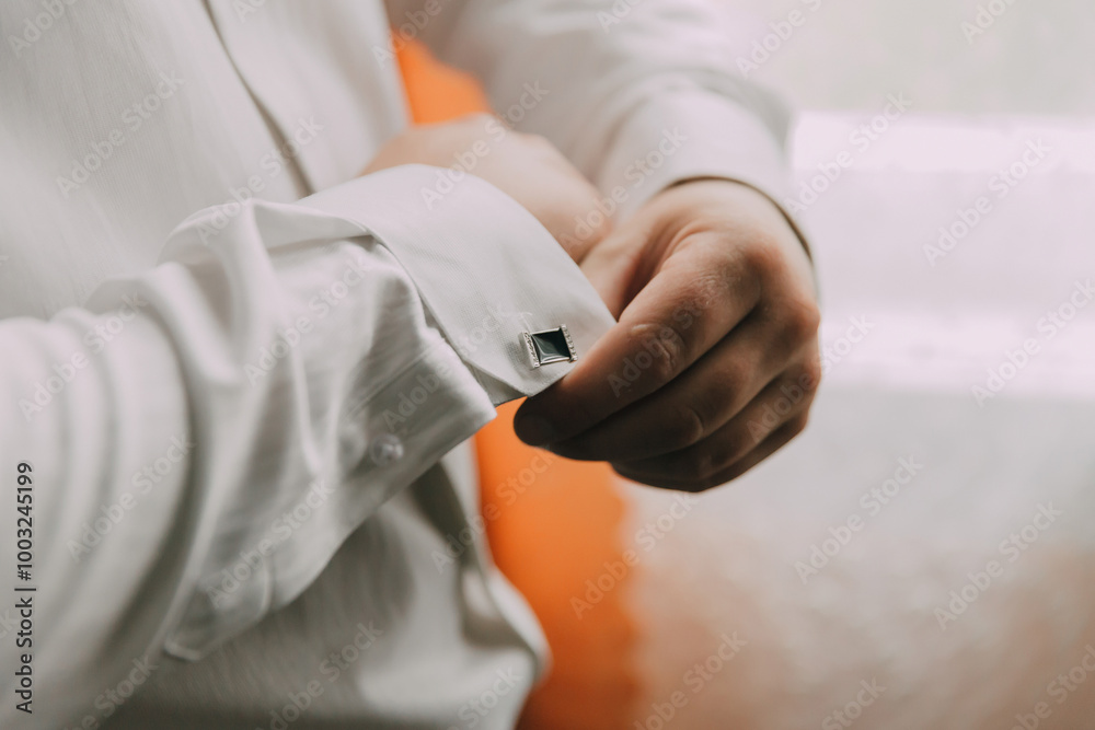 A man is getting dressed and adjusting his cufflinks. Concept of formality and attention to detail, as the man carefully prepares his outfit A man is getting dressed and adjusting his cufflinks. Concept of formality and attention to detail, as the man carefully prepares his outfit