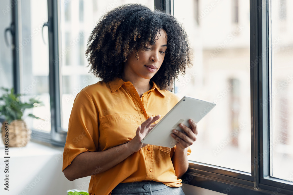 Entrepreneur woman using her digital tablet while standing in a modern startup Entrepreneur woman using her digital tablet while standing in a modern startup