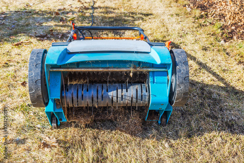 Electric lawn scarifier in spring garden during lawn maintenance with blades and mechanism. photo