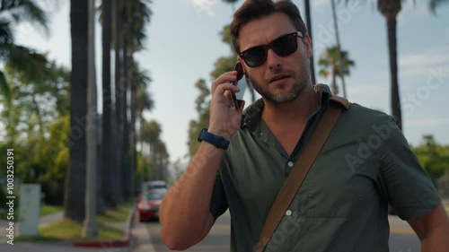 Young american man with surprised facial expression hold smartphone in his hands, typing message, chatting with friends in social networks, playing online game on Beverly Hills, Los Angeles.