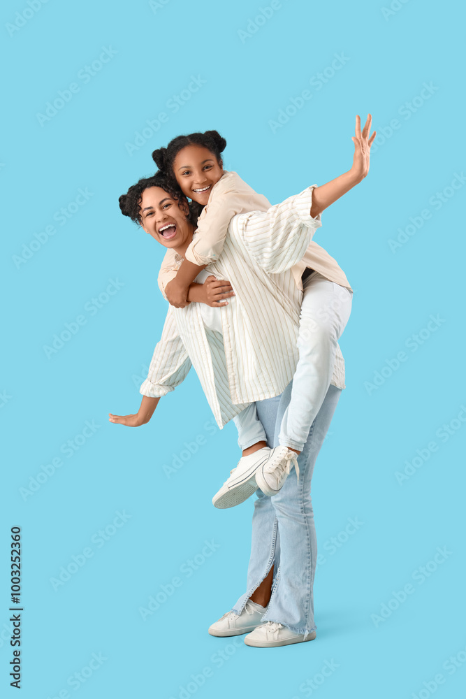 Happy young African-American woman with her daughter on blue background Happy young African-American woman with her daughter on blue background