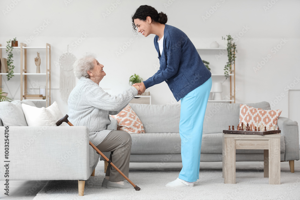 Young African-American female medical worker helping elderly woman in nursing home Young African-American female medical worker helping elderly woman in nursing home