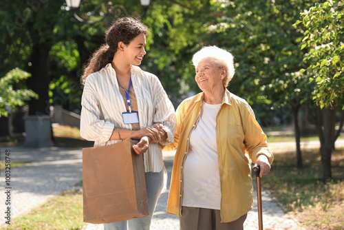 Young African-American female medical worker walking with elderly woman outdoors