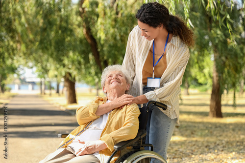 Young African-American female medical worker with elderly woman on wheelchair outdoors