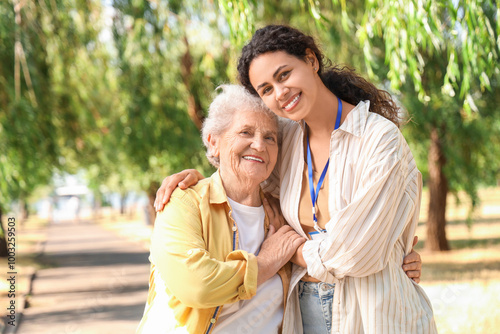 Young African-American female medical worker hugging with elderly woman outdoors