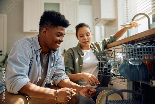 Young happy couple using dishwasher in  kitchen. photo