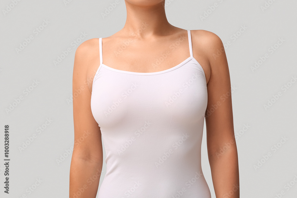 Young woman in tank top with beautiful breasts on grey background, closeup Young woman in tank top with beautiful breasts on grey background, closeup