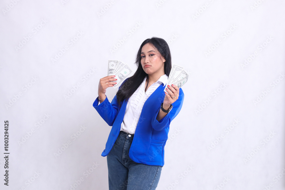 beautiful adult office woman wearing blue formal suit standing pouting to camera hands holding dollar bills to right left front isolated white background. for transaction, finance, business content beautiful adult office woman wearing blue formal suit standing pouting to camera hands holding dollar bills to right left front isolated white background. for transaction, finance, business content