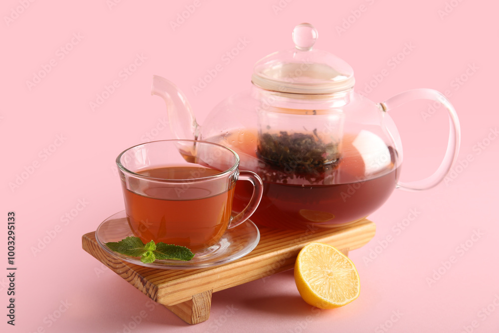 Beautiful composition with glass tea pot, lemon and wooden tray on pink background Beautiful composition with glass tea pot, lemon and wooden tray on pink background