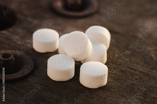 Photos White salt tablets for water softening lying on a rustic wooden countertop (sele