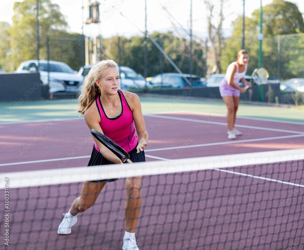 Obraz premium Female player playing tennis in tennis court outdoor behind the net