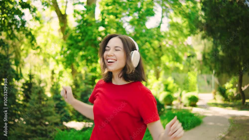 A Joyful Young Woman Radiating Vitality is Fully Enjoying Uplifting Music While Relaxing in a Beautiful, Lush Green Park on a Perfect Day A Joyful Young Woman Radiating Vitality is Fully Enjoying Uplifting Music While Relaxing in a Beautiful, Lush Green Park on a Perfect Day