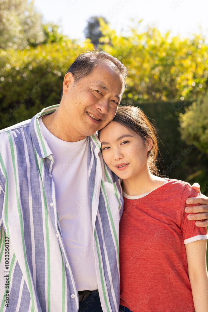 Fototapeta premium Embracing outdoors, smiling asian father and daughter enjoying quality family time together