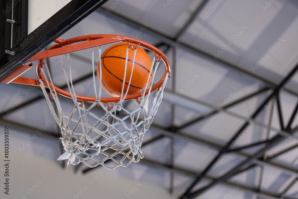 Basketball going through hoop in indoor court during game or practice Basketball going through hoop in indoor court during game or practice