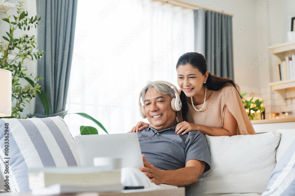 Senior spouses using laptop together sitting on couch at home. Elderly couple, hug and love on sofa with happy marriage, support and conversation of retirement home Senior spouses using laptop together sitting on couch at home. Elderly couple, hug and love on sofa with happy marriage, support and conversation of retirement home