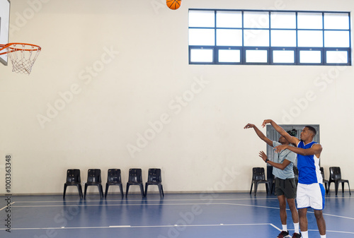 Playing basketball, african american men shooting hoops in court, focusing on technique, copy space photo