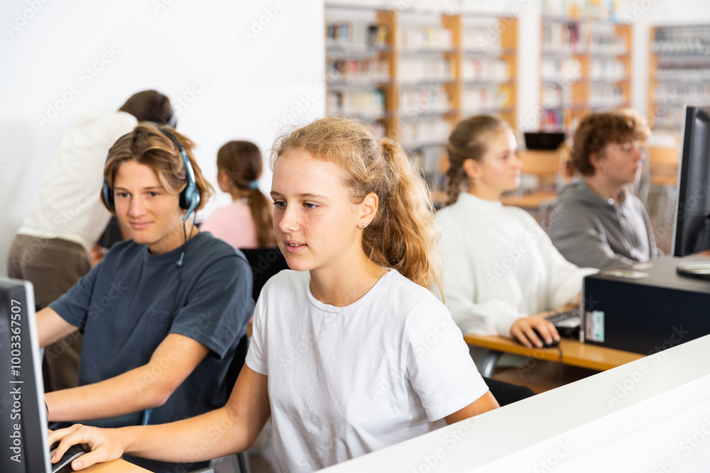 Obraz premium Teenager girls and boys studying in computer lab in library.