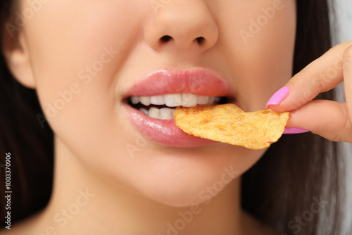 Young woman with beautiful lips eating potato chip, closeup