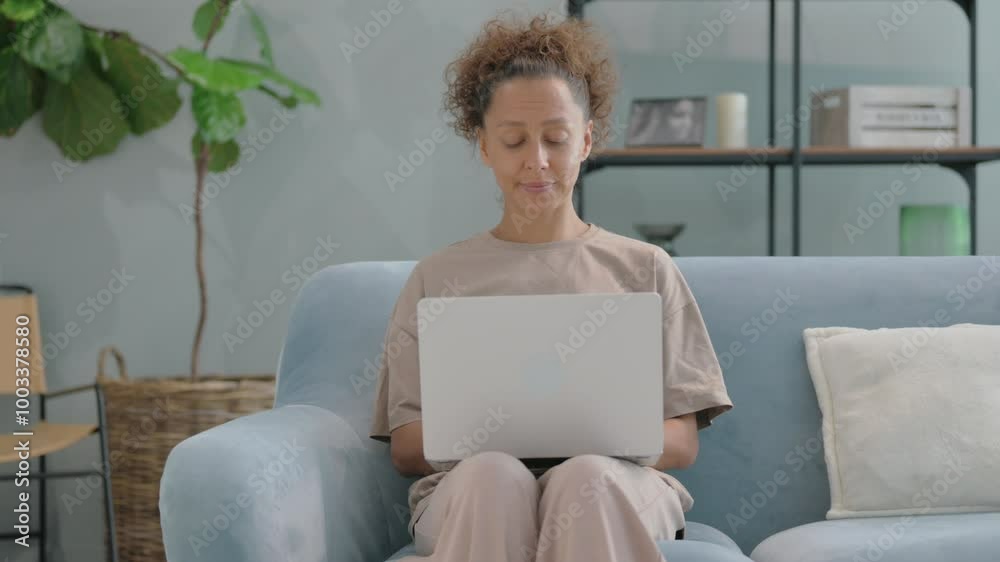 Hispanic Woman Working on Laptop while Sitting on Sofa Hispanic Woman Working on Laptop while Sitting on Sofa