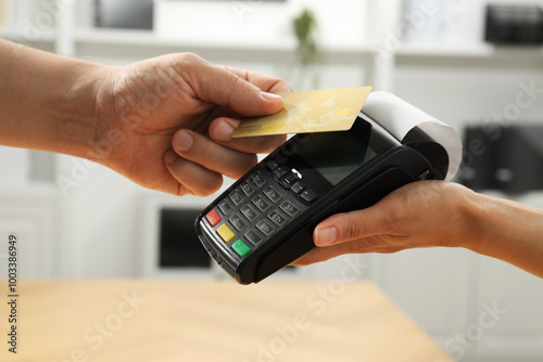 Customer paying with credit card using POS machine indoors, closeup photo