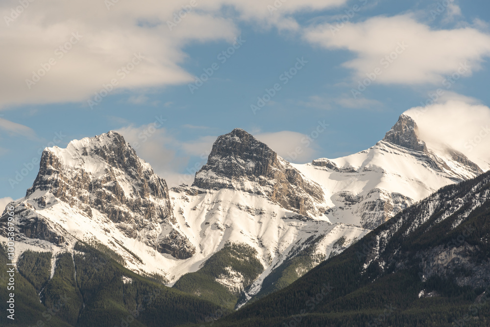 Obraz premium Incredible spring time views in Canmore, Alberta during May with Three Sisters Peaks in view with beautiful blue sky background on perfect day. 