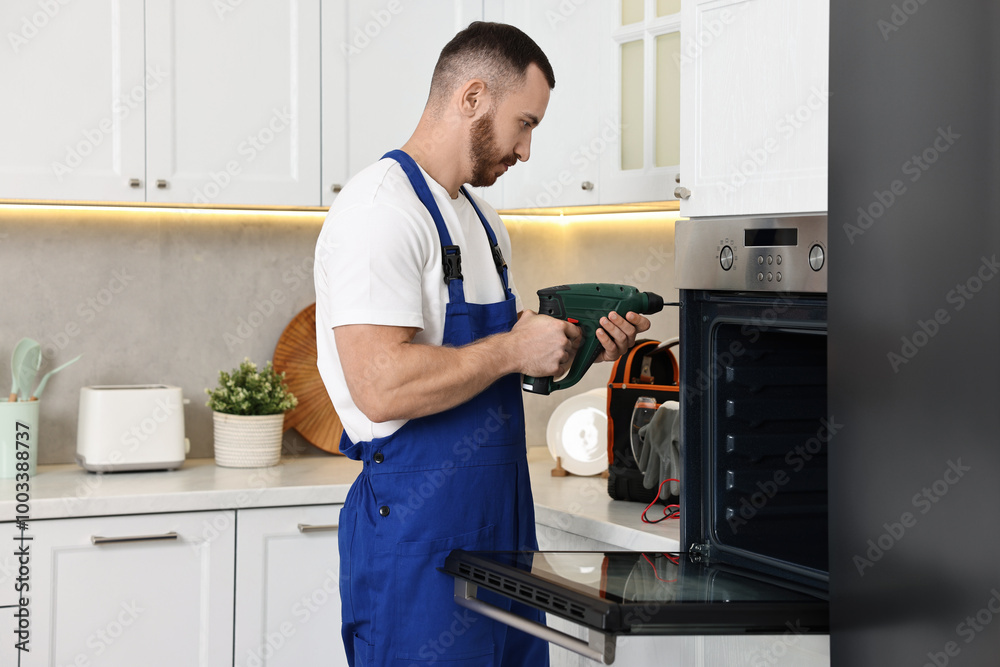 Repairman with drill fixing oven at home Repairman with drill fixing oven at home