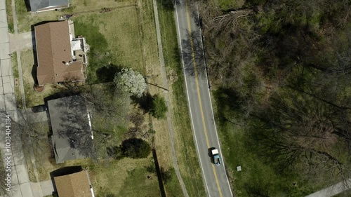 Pickup truck on a winding suburban road surrounded by trees and homes, capturing the essence of community living and the beauty of everyday journeys in a peaceful neighborhood.