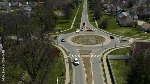 A clear view of a suburban roundabout, featuring landscaped green spaces and vehicles navigating the circular intersection, illustrating the charm of modern suburban planning.