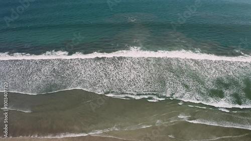 A stunning view of waves crashing against the beach in Bali, Indonesia, showcasing the vibrant energy of the ocean and the beauty of the tropical shoreline.