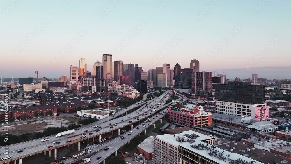 Aerial video of downtown Dallas, Texas during sunrise with highways, traffic and skyscraper buildings in the background.