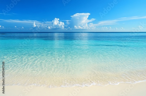 Crystal clear turquoise water laps onto a pristine white sandy beach with a vibrant blue sky and fluffy white clouds.