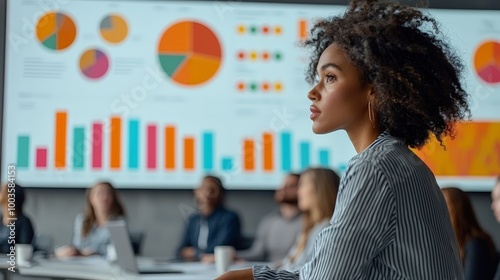 A woman attentively listens in a business meeting with data visuals in the background. photo