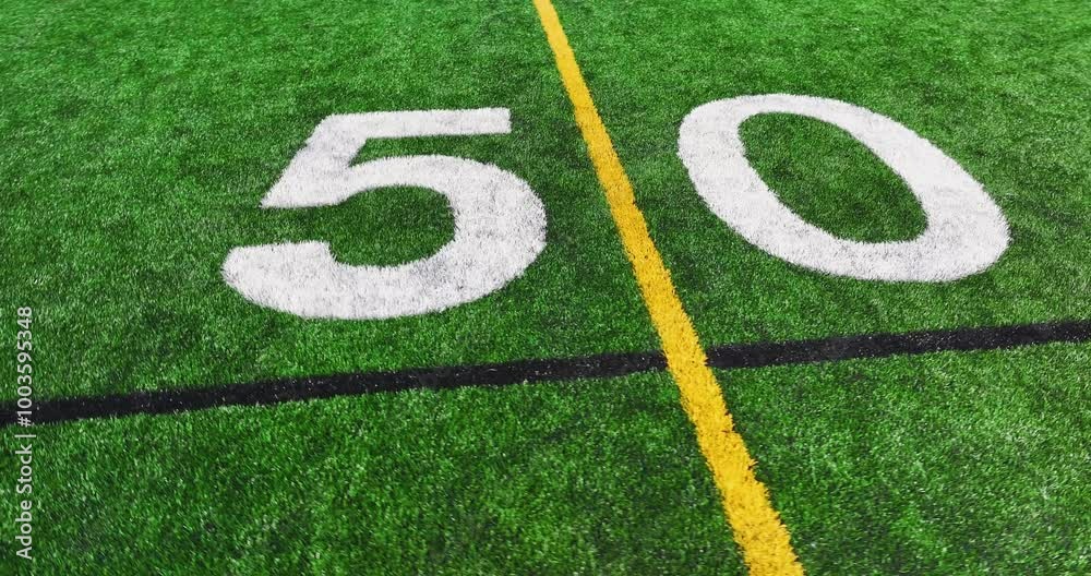 Aerial video of a typical synthetic turf football field 50 yard line in white. Aerial video of a typical synthetic turf football field 50 yard line in white.