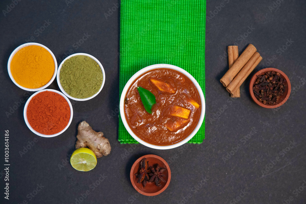 chicken fry, chicken gravy, mutton gravy along with lemon, ginger, garlic, chili powder, coriander powder, turmeric powder, cinnamon and spices on white plate and white bowl in the side of green towel chicken fry, chicken gravy, mutton gravy along with lemon, ginger, garlic, chili powder, coriander powder, turmeric powder, cinnamon and spices on white plate and white bowl in the side of green towel