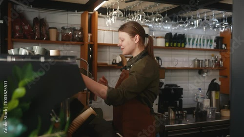 Young woman barista making coffee in the cafe