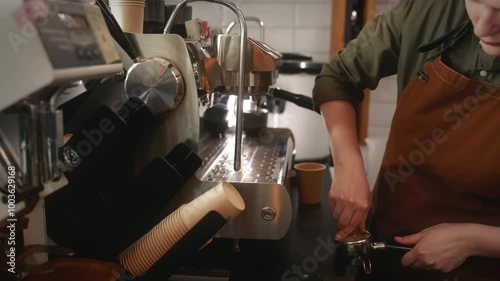 Barista hands with portafilter and coffee tamper making espresso
