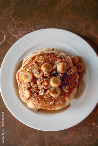 Overhead view of a stack of pancakes with bananas vertical