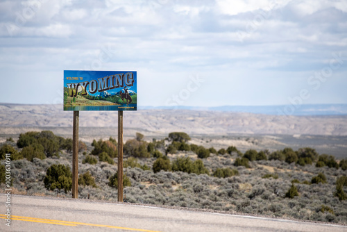 Welcome to Wyoming sign along rural highway overlooking valley